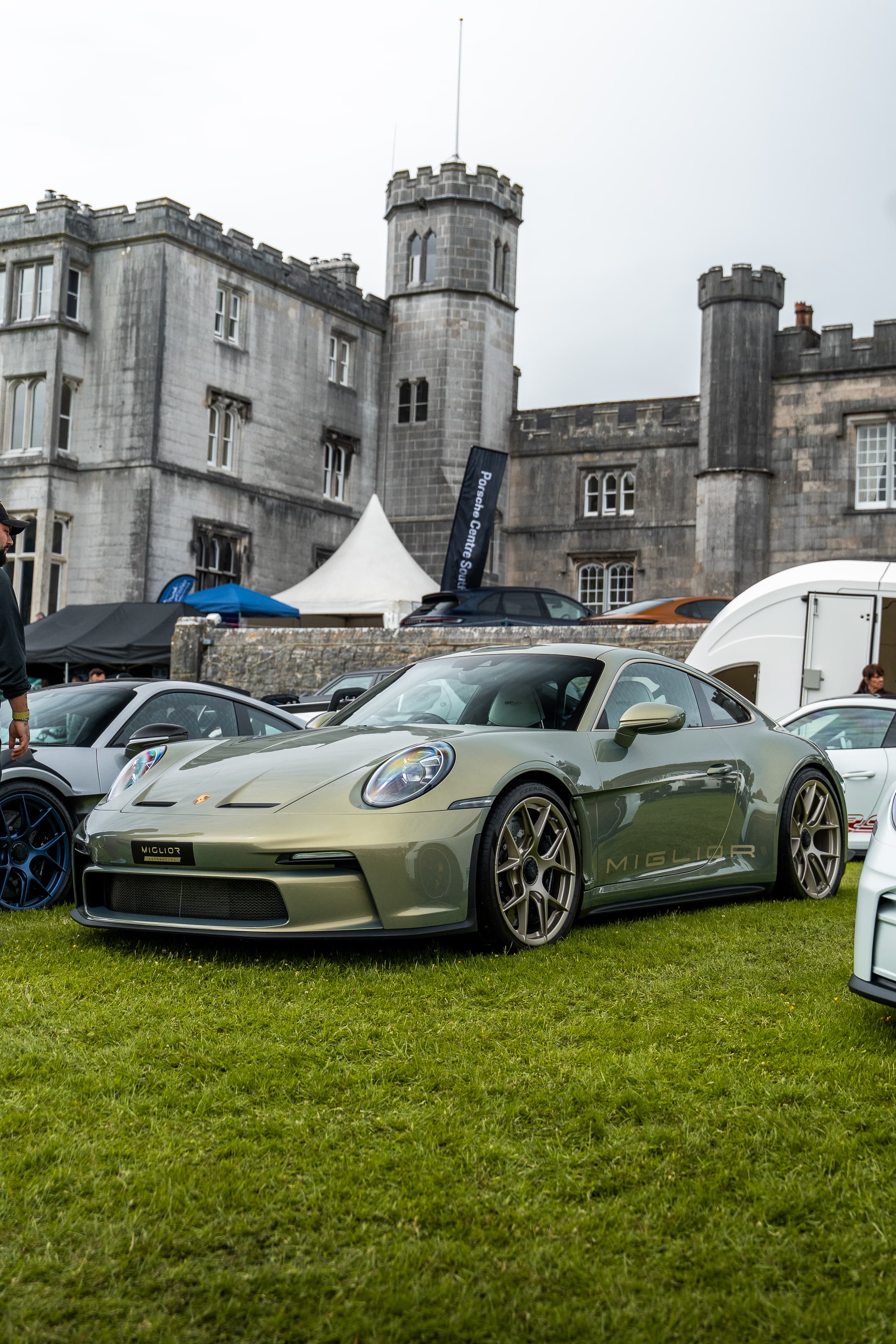 A Porsche 911 GT3 parked on the grass in front of a historic stately home at a Renntag event