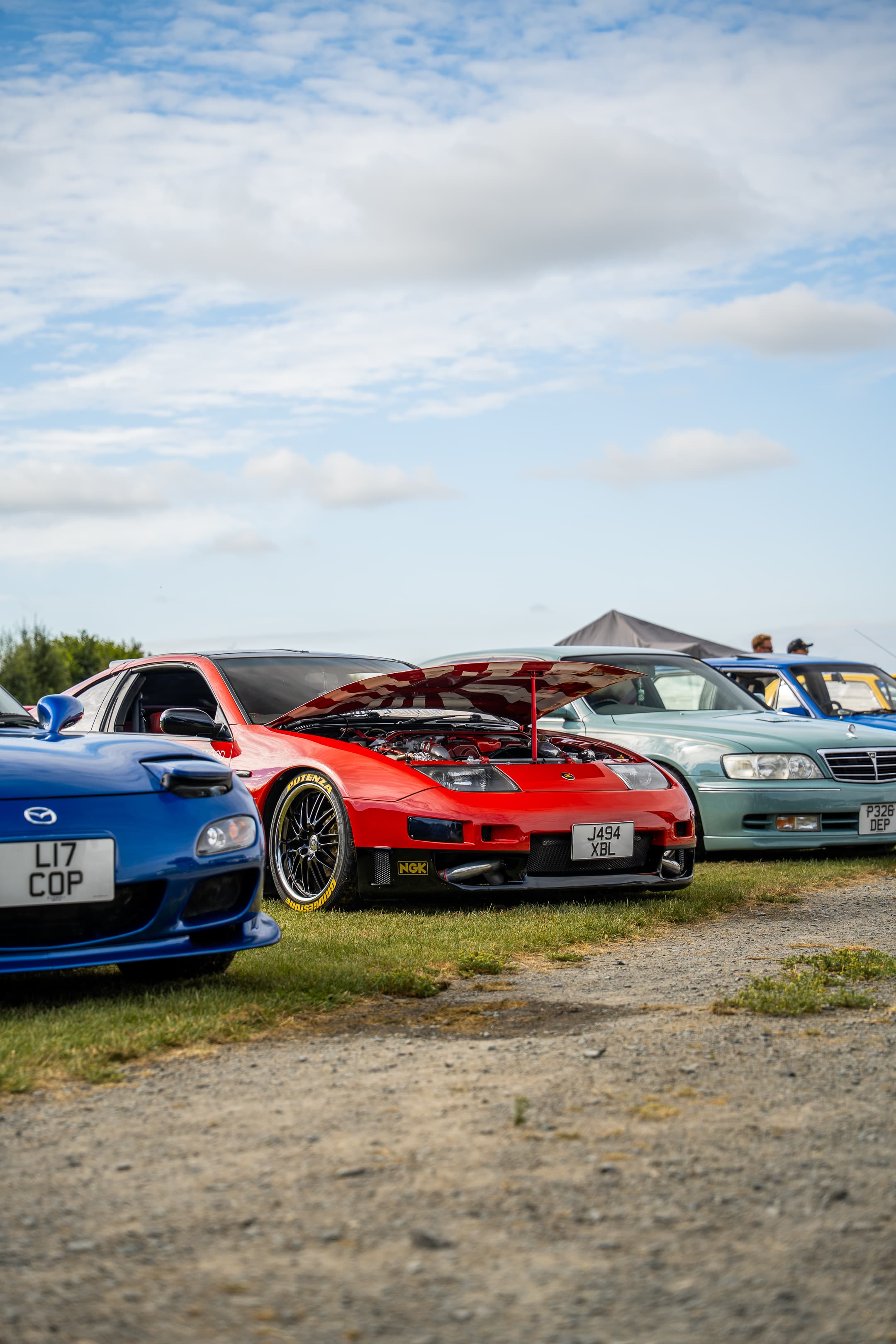 Modified sports cars parked in a row at an outdoor WUN car meet
